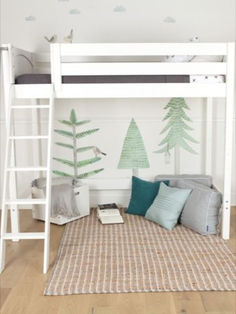 a white bunk bed with green trees painted on the wall above it and pillows below