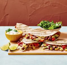 three quesadillas on a cutting board with salsa and lime