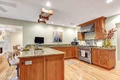 a large kitchen with wooden cabinets and stainless steel appliances, along with hardwood flooring