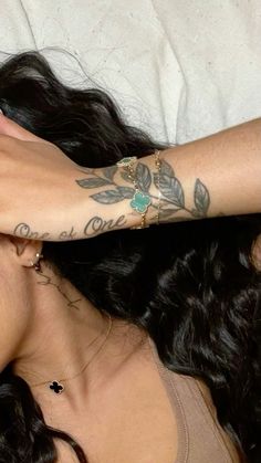 a woman laying in bed with her arm wrapped around another woman's head and tattoos on her arms