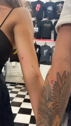 a man and woman holding hands with tattoos on their arms in a store display area