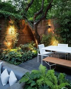 an outdoor dining table and bench in the middle of a garden