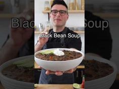 a man holding a bowl of black bean soup in front of his face and the words black bean soup above it