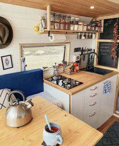 a small kitchen with a tea kettle on the counter and shelves above it that are filled with spices