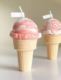 two ice cream cones with pink and white icing on them, one has a tag attached to the top