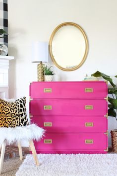 a pink dresser with leopard print on it and a white chair in front of it