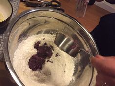 a person mixing ingredients in a bowl on a table