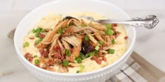 a white bowl filled with mashed potatoes topped with meat and green onions