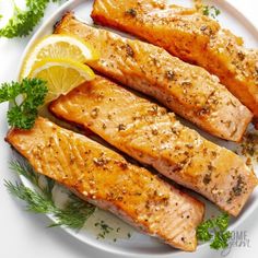 some salmon on a plate with lemon wedges and parsley