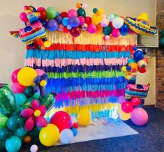 a room filled with balloons and streamers next to a wall covered in tassels