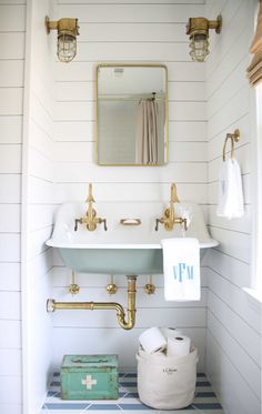 a white bathroom with gold fixtures and blue tile flooring on the walls, along with an antique sink