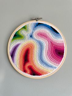 a multicolored circular wall hanging in front of a gray wall with a wooden frame