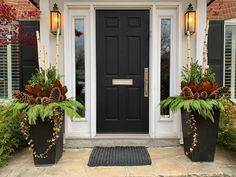 two large planters with pine cones are on the front porch