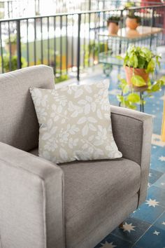 a chair with a pillow on top of it in front of a balcony and potted plants