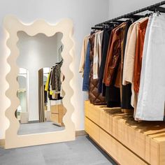 an open closet with clothes hanging on rails and a mirror in the middle, next to it