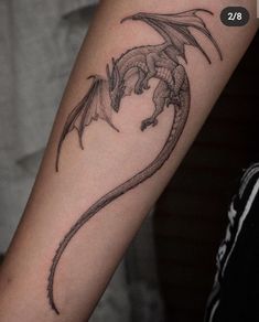 a black and white photo of a dragon tattoo on the arm