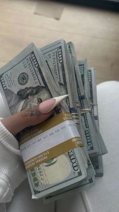 a woman's hand holding stacks of money with a pencil sticking out of it