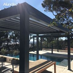 a wooden bench sitting under a pergoline covered roof next to a swimming pool