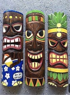 three tiki masks are lined up on the wall