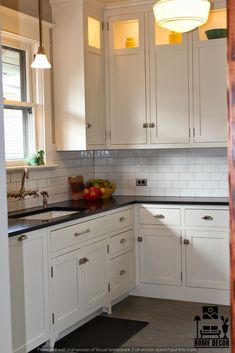 a kitchen with white cabinets and black counter tops