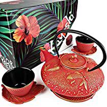 a red tea set with matching cups and saucers in front of a black box