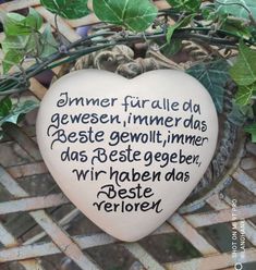 a heart shaped stone sitting on top of a basket next to green leaves and ivy