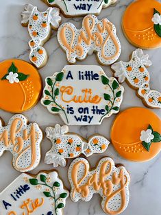 some cookies that are decorated to look like oranges and white with the words little cutie is on the way