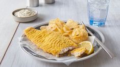 fish and chips on a plate next to a glass of water