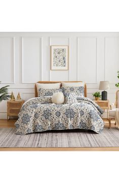 a bed with blue and white bedspread in a room next to a chair