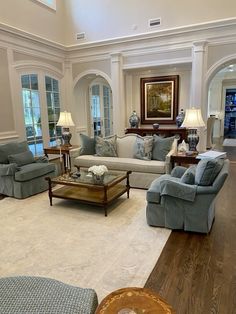 a living room with couches, chairs and tables in the middle of the room