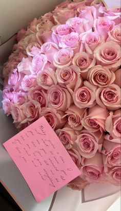 a large bouquet of pink roses is next to a note