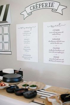 two menus are hanging on the wall above a table with plates and utensils