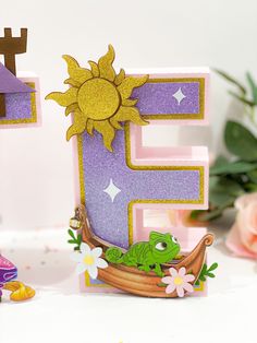 the letter e is made out of paper and has a frog in a boat on it