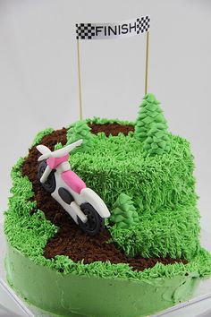 a cake with green frosting and dirt on it, decorated with a car driving through the grass