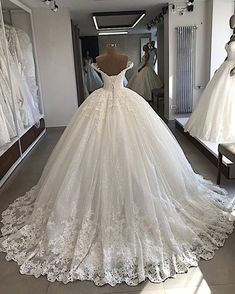 a white wedding dress on display in a room with mannequins and dresses