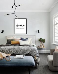 a bedroom with white walls and gray carpeted flooring, a bed in the center