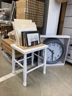 a white table with pictures and a clock on it in a room filled with other items