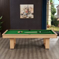 a pool table in the middle of a living room with a painting on the wall