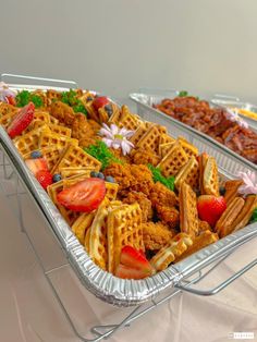 two serving trays filled with waffles, strawberries and other food items