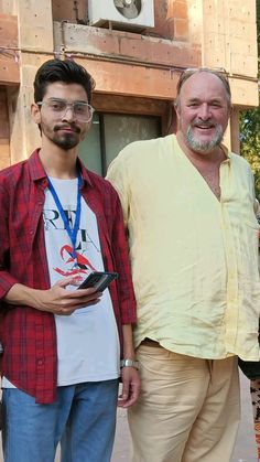 two men standing next to each other in front of a building