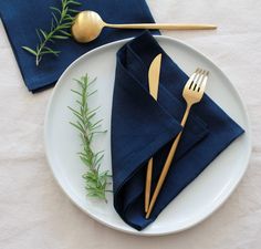 a white plate topped with blue napkins and gold utensils