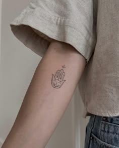 a woman's arm with a small hand tattoo on the left side of her arm