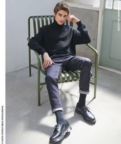 a young man sitting on top of a green chair next to a white wall and window