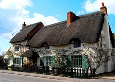 an old thatched roof house with green shutters