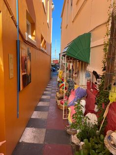 there are many plants and umbrellas on the side of this street that is lined with buildings