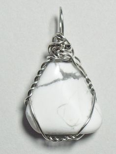 a white stone pendant is shown on a silver plated chain with a clasp around it