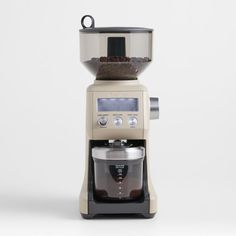 an espresso machine sitting on top of a white table next to a blender