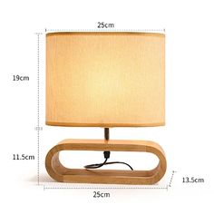 a wooden table lamp with a beige shade on the base and measurements for each light