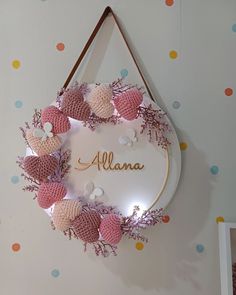 a pink and white wreath with name on it hanging from the side of a wall