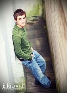 a young man is leaning against the wall